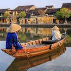 Vietnamese women paddling in old town in Hoi An city, Vietnam. Hoi An is situated on the east coast of Vietnam. Its old town is a UNESCO World Heritage Site because of its historical buildings.