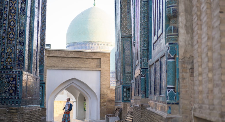 Senior woman on the path between memorial buildings of Shakhi Zinda Mausoleum which is memorial complex of Islamic architecture from 9 to 12. century in Samarkand, Uzbekistan
1129859652
ancient, architecture, art, asia, building exterior, craft, cultures, decoration, east, entrance, facade, famous place, history, indigenous culture, monument, multi colored, old, pattern, photography, religion, sky, spirituality, travel destinations, unesco world heritage site, mausoleum, silk road, tomb, samarkand, tribal art, central asia, mosaic, ceramics, cemetery, memorial, uzbekistan, tile, turquoise colored, persian culture, photography themes, footpath, single lane road, horizontal, women, one woman only, senior adult, shah-i-zinda
A woman looking up at the memorial buildings of Shah-I-Zinda Mausoleums in Samarkand, Uzbekistan