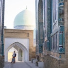 Senior woman on the path between memorial buildings of Shakhi Zinda Mausoleum which is memorial complex of Islamic architecture from 9 to 12. century in Samarkand, Uzbekistan
1129859652
ancient, architecture, art, asia, building exterior, craft, cultures, decoration, east, entrance, facade, famous place, history, indigenous culture, monument, multi colored, old, pattern, photography, religion, sky, spirituality, travel destinations, unesco world heritage site, mausoleum, silk road, tomb, samarkand, tribal art, central asia, mosaic, ceramics, cemetery, memorial, uzbekistan, tile, turquoise colored, persian culture, photography themes, footpath, single lane road, horizontal, women, one woman only, senior adult, shah-i-zinda
A woman looking up at the memorial buildings of Shah-I-Zinda Mausoleums in Samarkand, Uzbekistan