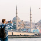 Tourist photographing Istanbul skyline with smart phone, rear view - stock photo