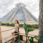 A woman sitting near the main pyramid at Chichen Itza in Mexico