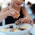 Woman squeezes lemon on to oysters while dining alone