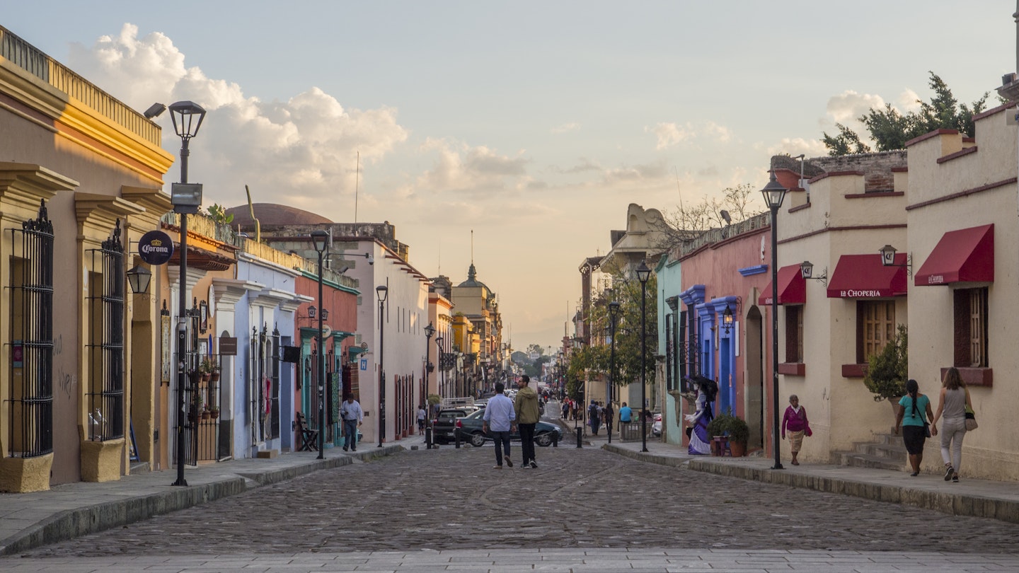People wander down a cobble stone street lined with colorful colonial buildings in Oaxaca, Mexico © Melissa Kuhnell