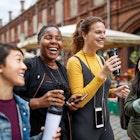 A group of friends walk through a city street holding coffee cups.