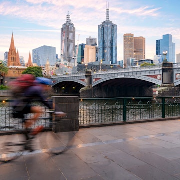Australian people cycling for exercise near Yarra River with view of the Melbourne City Financial District with skyscrapers in morning at Melbourne, Victoria, Australia.