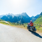 One person riding bike on Ha Giang motorbike loop, famous travel destination bikers easy riders. Ha Giang karst geopark mountain landscape in North Vietnam. Winding road in stunning scenery. License Type: media Download Time: 2022-05-04T03:08:59.000Z User: Is Editorial: No purchase_order: